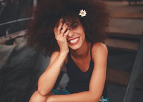 pexels-photo-1848565-1848565-1 Cheerful woman wearing ripped jeans and curly hair with flower, enjoying a sunny day outdoors.